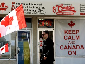 'N Voetganger maak hul pad verby vlae en 'n' hou kalm en Kanada aan 'bord buite O'Canada -toerusting in Edmonton, Alta.